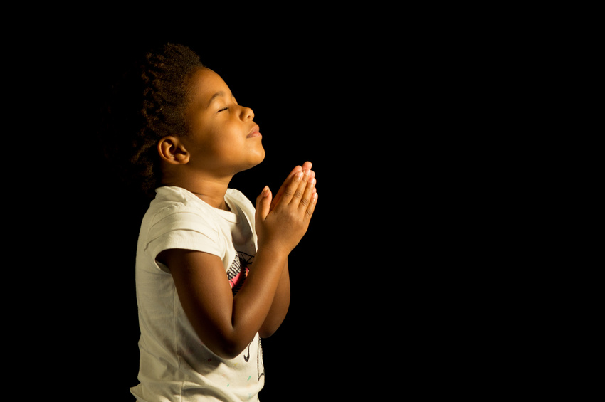 A young child prays to God.